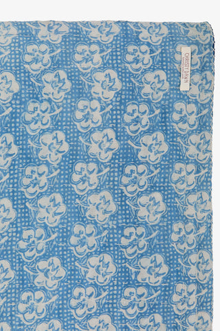 Blue fabric with white floral pattern, featuring a brand label on the right corner.