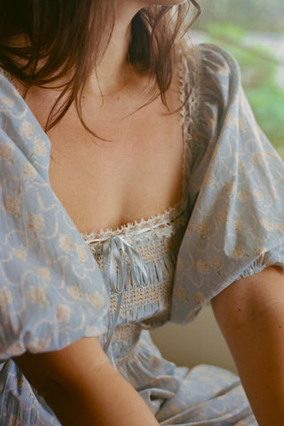 Woman wearing a light blue floral dress with a blurred background