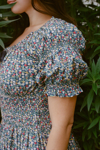 Person wearing a floral dress standing among green plants