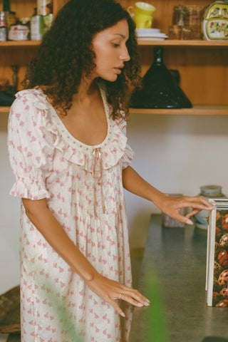 Woman in a low scoop floral dress standing in a kitchen