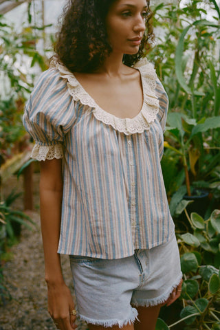 Woman wearing a striped blouse with lace details in a garden setting