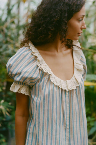 Woman wearing a striped blouse with lace details in a natural setting