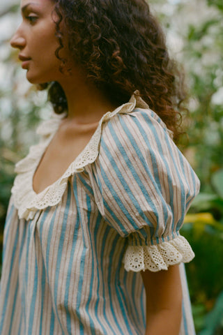 Woman wearing a striped blouse with lace details in an outdoor setting