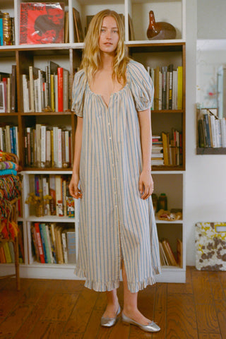 Woman in a striped dress standing in front of a bookshelf