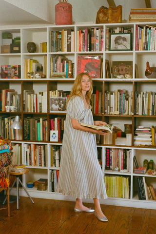 Woman standing in a room filled with bookshelves and books.