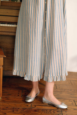 Person wearing striped pants and silver shoes on a wooden floor.