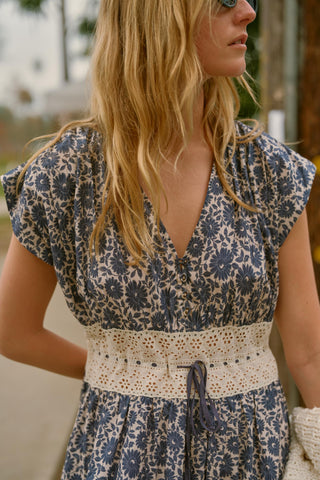 Woman wearing a floral dress with a contrast lace waist in an outdoor setting