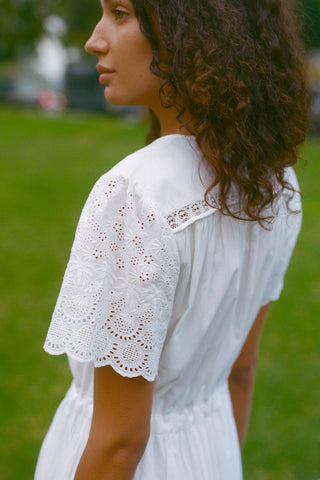 Woman wearing a white dress with lace details in an outdoor setting