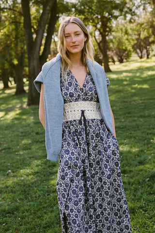 Woman wearing a floral dress and light blue cardigan in a park setting
