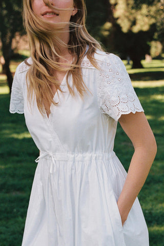 Woman wearing a white dress with lace details in a park setting