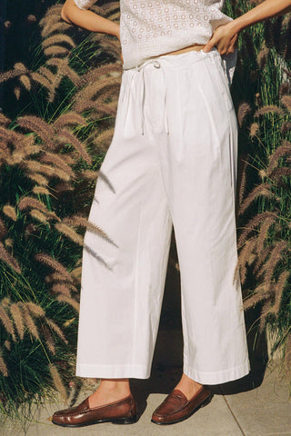 Person wearing white pants standing in front of tall grasses