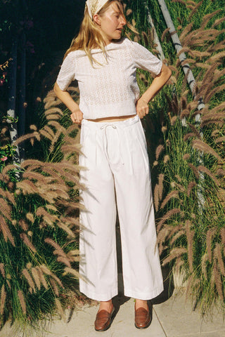 Woman in a white outfit standing among tall grasses