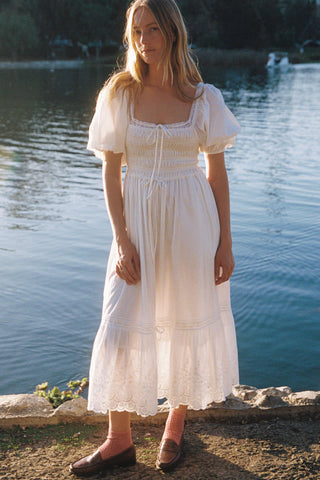 Woman in a white dress standing by a body of water