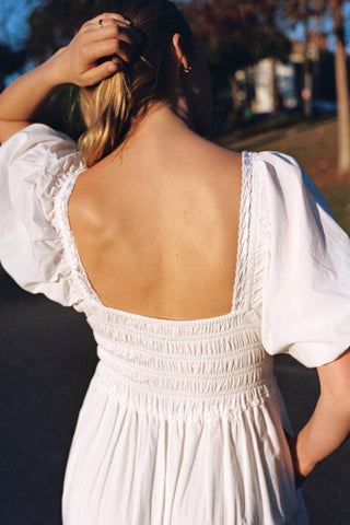 Woman wearing a white dress with open back in an outdoor setting