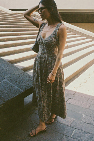 Woman in a patterned dress standing on stone steps outdoors