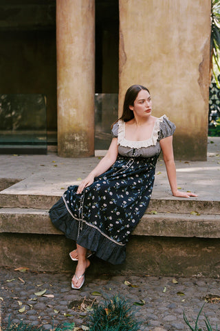 Woman in a floral dress sitting on stone steps outdoors