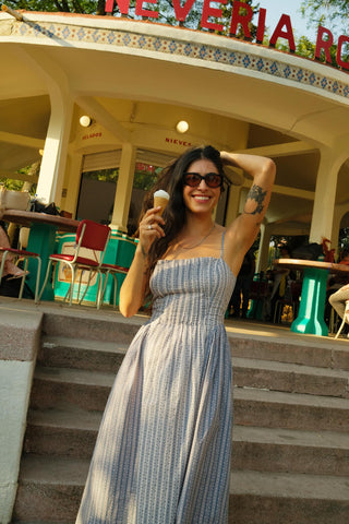 Woman in a strapless dress standing on steps in front of a building with 'Neveria' sign.