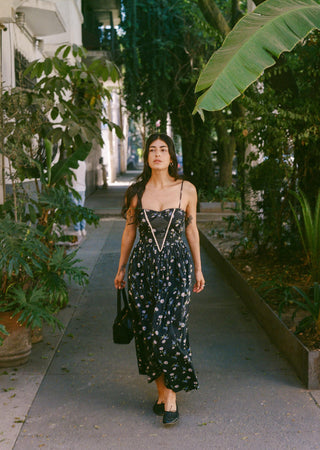 Woman walking down a sunlit path lined with trees and plants