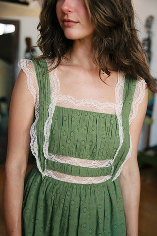 Woman wearing a green dress with lace details in an indoor setting