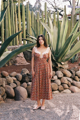 Woman in a floral dress standing in front of cacti and rocks