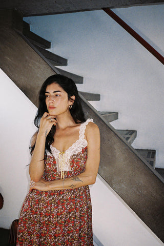 Woman in a floral dress standing on a staircase with a neutral background