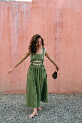 Woman in a green dress standing against a pink wall