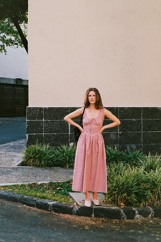 Woman in a pink dress standing outdoors against a building.
