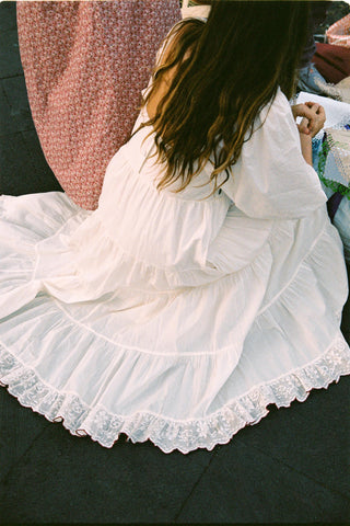 Person wearing a white lace dress crouching on the floor.