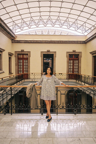 Woman standing in a large, open building with high ceilings and marble floors.