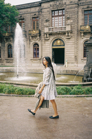 Woman walking in front of a historic building with a fountain