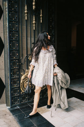 Woman standing in front of a decorative door holding a coat.