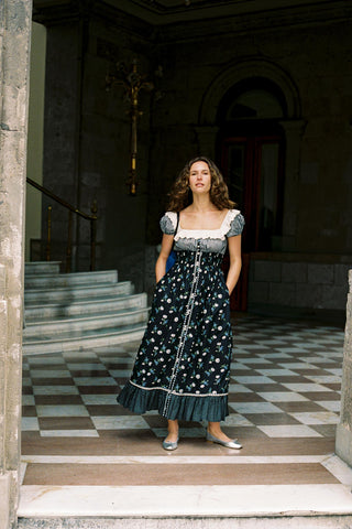 Woman in a dark floral dress standing in an elegant interior setting