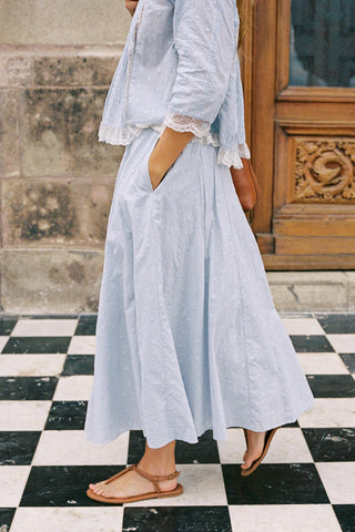 Person wearing a light blue outfit standing on a black and white checkered floor.