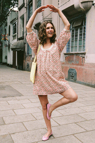 Woman in a floral dress posing on a street with buildings in the background
