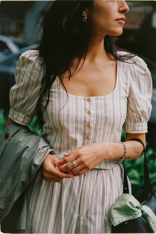 Woman wearing a striped top and pants with puffed sleeves in an outdoor setting