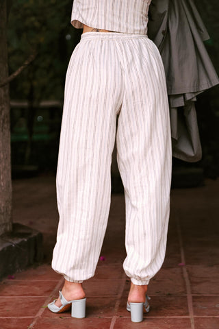 Person wearing white striped pants and a matching top on a blurred background
