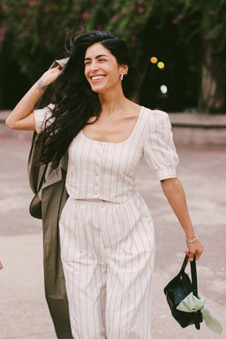 Woman in a striped matching outfit walking outdoors with a blurred background