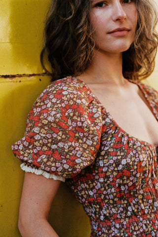 Woman wearing a red floral dress against a yellow background