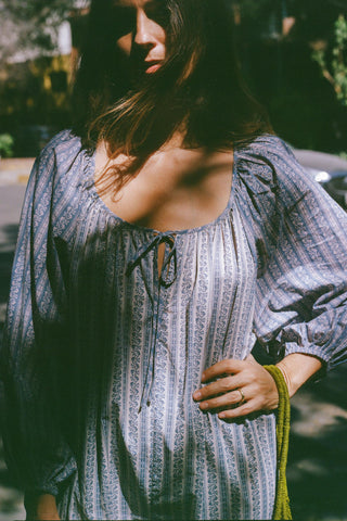 Woman wearing a patterned dress with a blurred outdoor background