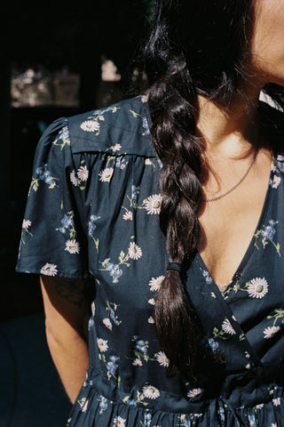 Woman wearing a dark floral dress with a blurred background