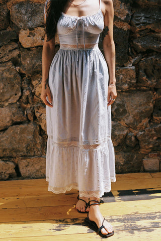 Woman wearing a light blue dress standing against a stone wall.