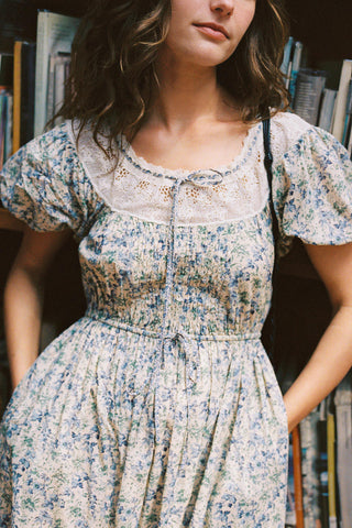 Woman wearing a floral dress in a bookstore setting