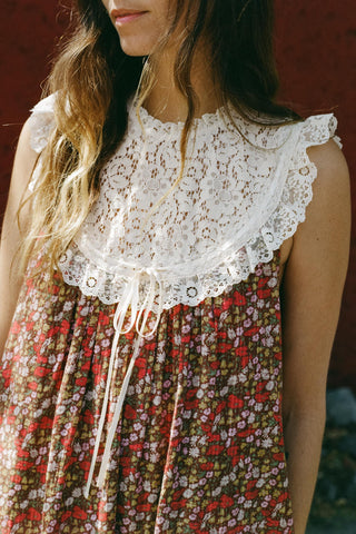 Woman wearing a floral dress with a lace bib against a blurred background