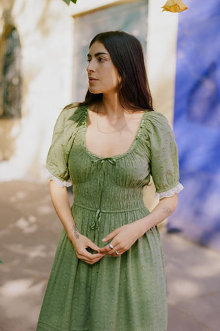 Woman in a green dress standing outdoors with a blurred background