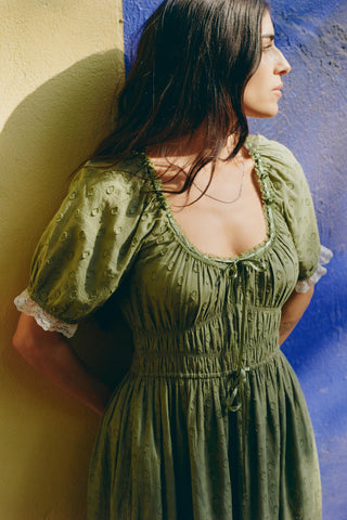 Woman wearing a green dress against a colorful wall.
