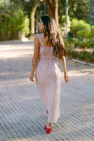Woman in a pink dress walking on a paved path in a park.
