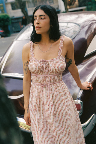 Woman in a patterned dress standing next to a vintage car