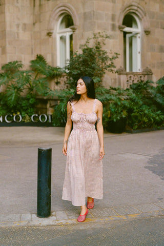 Woman in a pink dress standing in front of a building with 'COCO' branding.
