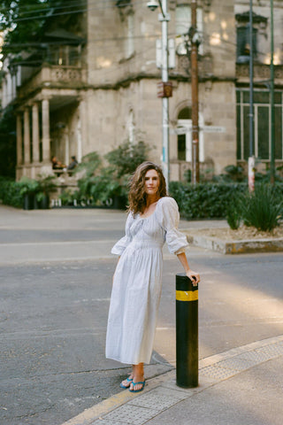 Woman in a white dress standing on a street with a building in the background