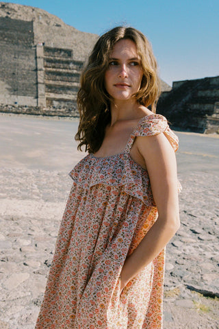 Woman in a floral dress standing in front of ancient ruins